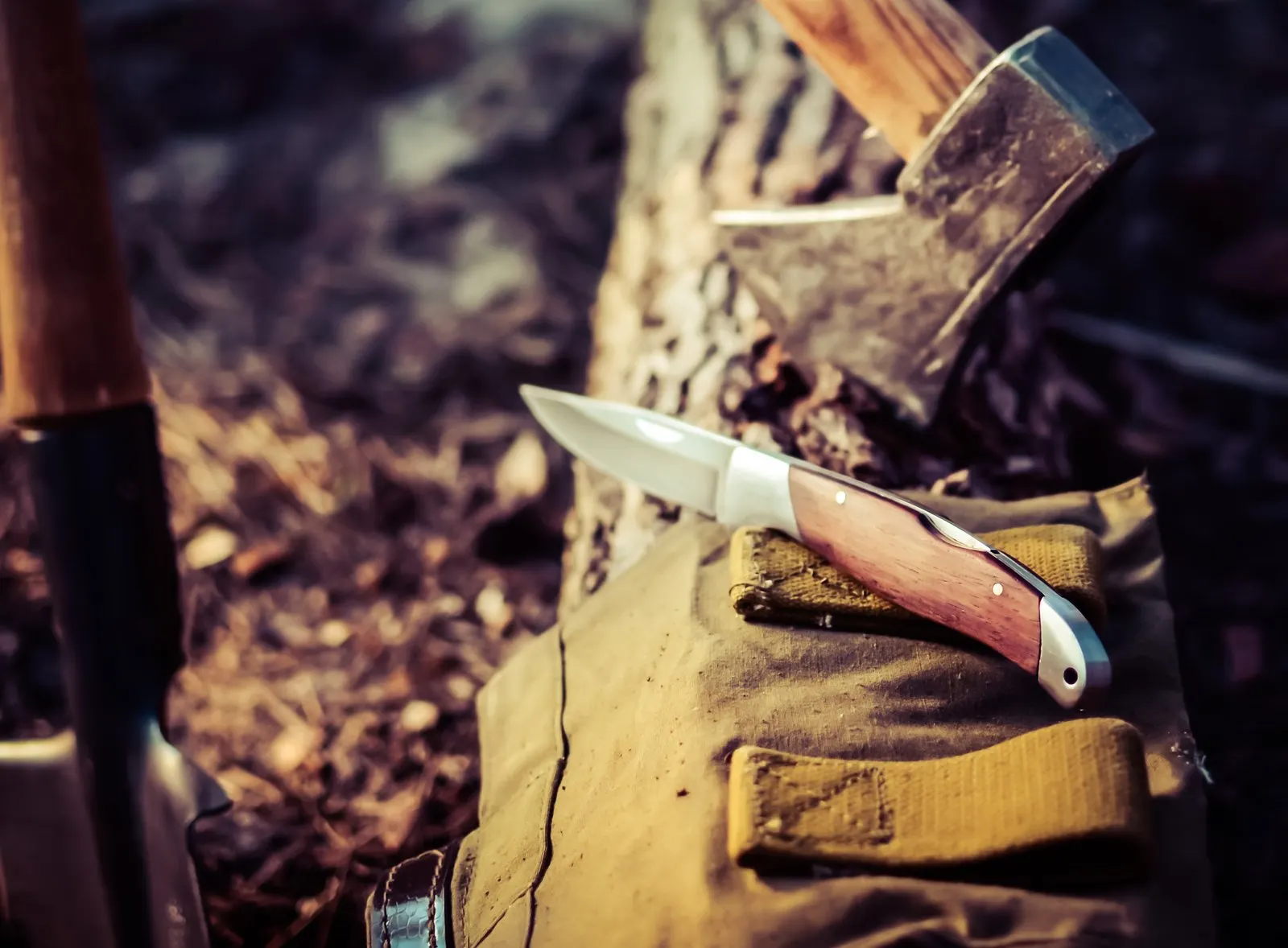Camping hatchet and knife resting on a tan pack outdoors