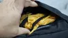Yellow rain cover tucked in a zippered pocket at the bottom of the Teton Scout