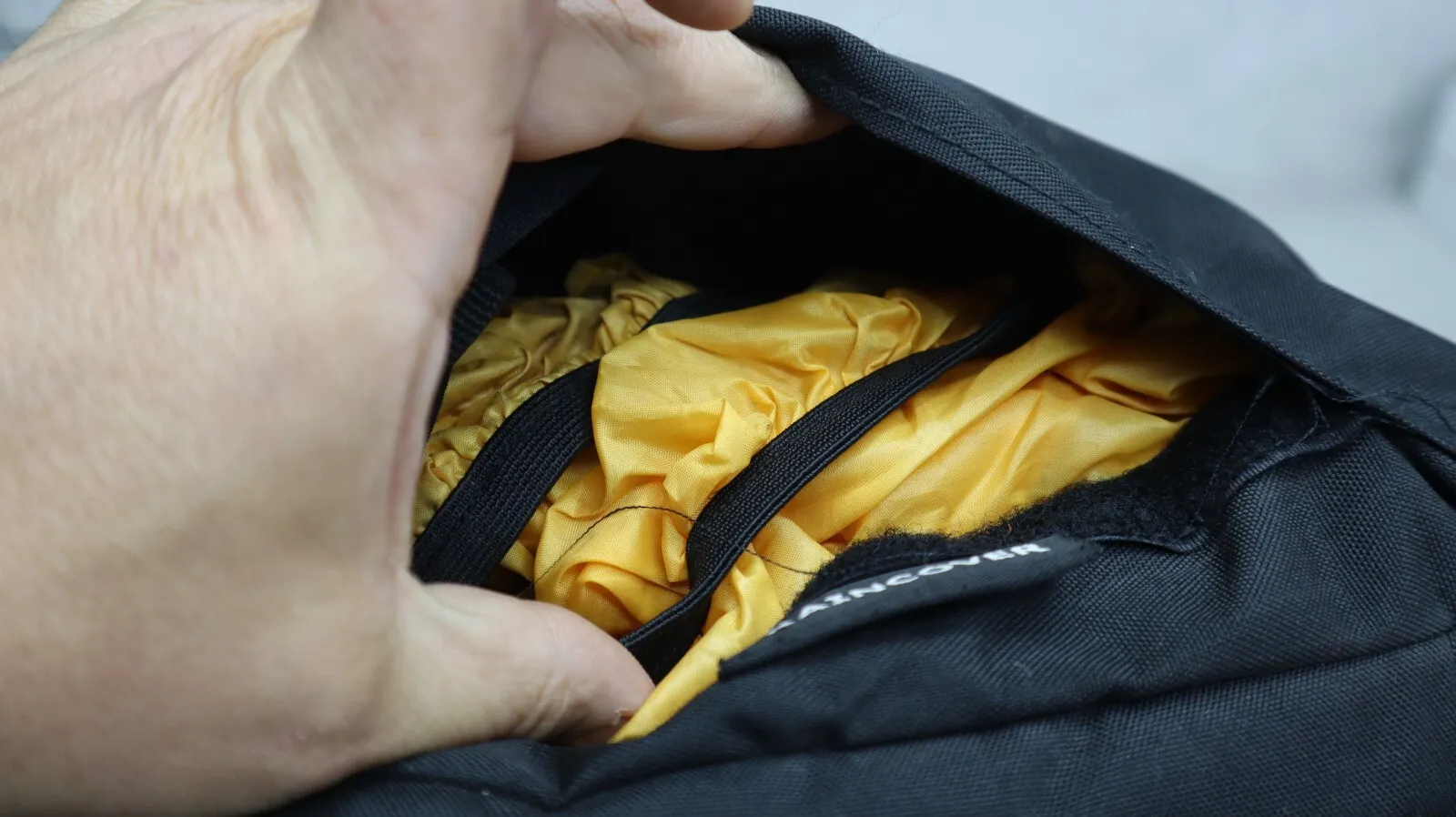 Yellow rain cover tucked in a zippered pocket at the bottom of the Teton Scout