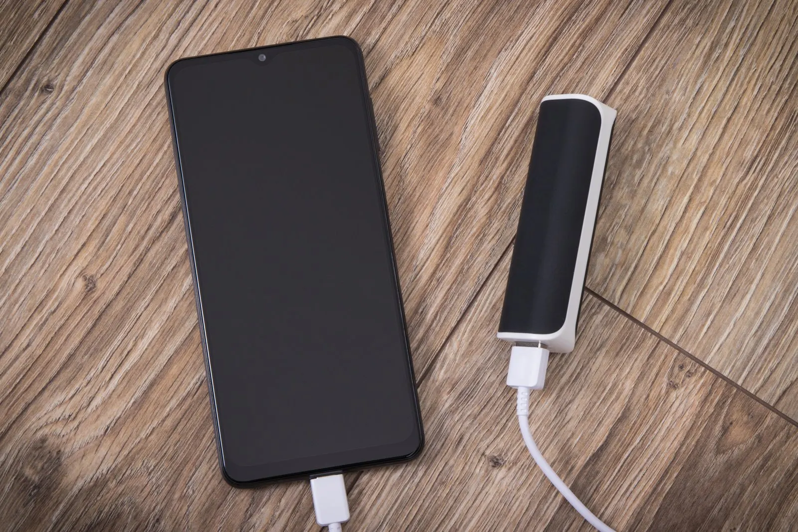 Emergency power bank charging a phone on a wooden table
